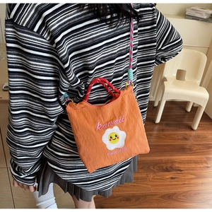 Dettaglio borsa a secchiello in nylon arancione con ricamo uovo fritto e tracolla colorata
