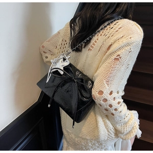 Detail of black patent leather underarm bag featuring a large bow and metallic star charms