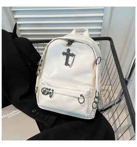 Detail of white PU leather backpack with vintage metal cross and chains in a metal basket