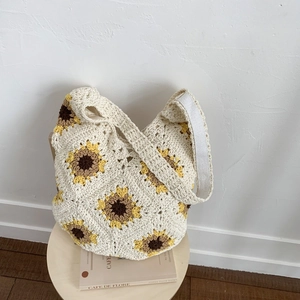 Detail view of handmade woven tote bag featuring vibrant yellow sunflower patterns and canvas strap