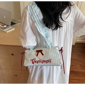 Detail of light blue checkered crossbody bag with red bow and heart patch embroidery
