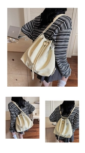 Detail of off-white drawstring backpack with silver heart charm and leather texture