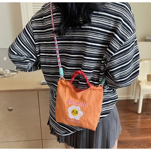 Dettaglio della borsa a secchiello in nylon arancione con ricamo a uovo e tracolla colorata