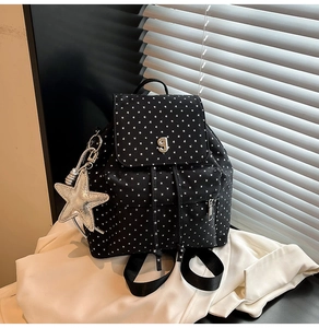 Detail view of black backpack with white star print and silver star metal pendant charm