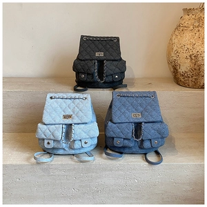 Detail of denim quilted backpacks in various blue tones with chain straps and metal locks