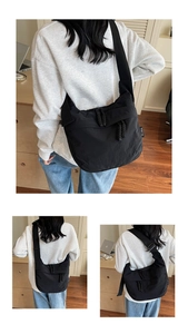 Detail of black nylon crossbody bag featuring adjustable wide strap and dual zipper closure