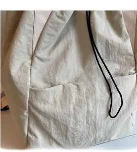Detail shot of the beige backpack showing the soft textured fabric and black drawstring