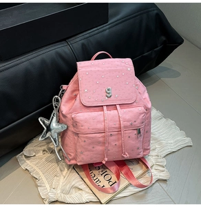 Detailed view of pink backpack with silver star patterns and glossy star charm attachment