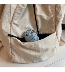 Detail view of the cream nylon bag's side pocket holding a blue umbrella for storage