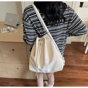 Close-up of a glossy white bucket bag in a warm home setting showing smooth texture