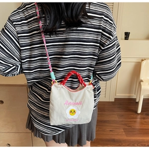 Dettaglio di una mini borsa a secchiello in tela con ricamo a uovo fritto e tracolle colorate