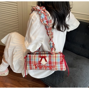 Detail of red and blue plaid handbag with bow and heart embroidery on white dress