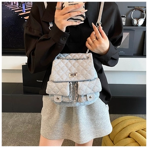 Detail of grey quilted denim backpack featuring silver chain straps and classic turn-lock