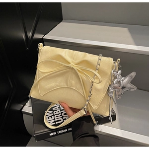 Detail of yellow pleated shoulder bag with bow, chain strap and star dog charms