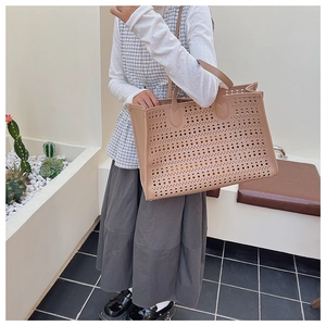 Détail de la texture perforée au laser sur ce sac cabas en cuir élégant de couleur beige clair