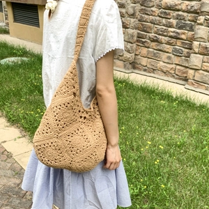Detail of hand-woven crochet tote bag with hollow floral patterns and wide shoulder strap