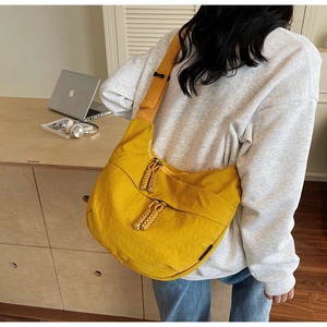 Detail of yellow crescent bag featuring dual zippers and woven rope pullers on nylon