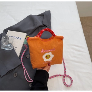 Dettaglio borsa a secchiello in nylon arancione con ricamo Kawaii e tracolla intrecciata