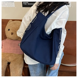 Detail view of navy blue canvas tote bag with white hollow letter print on the body