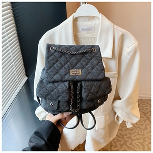 Detail of grey quilted denim backpack with silver chain strap and metal turn-lock closure
