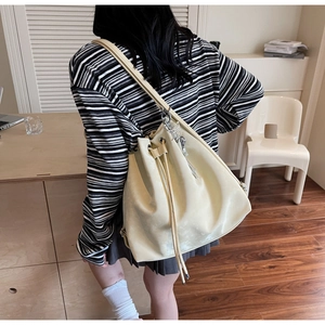 Detail of beige drawstring bucket bag with silver butterfly pendant and matte finish