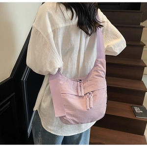Detail of light purple nylon dumpling bag showing wide strap and woven zipper pullers