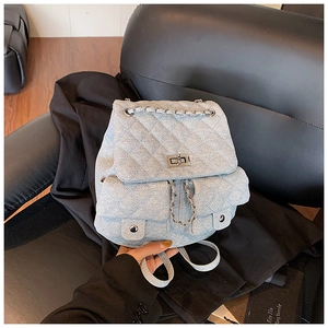 Detail showing denim quilted backpack with chain straps and turn-lock closure