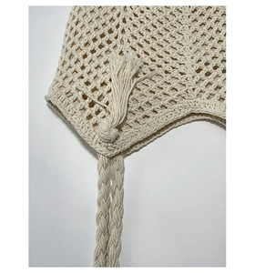Macro shot of beige woven bag featuring decorative pom-poms and fringe details