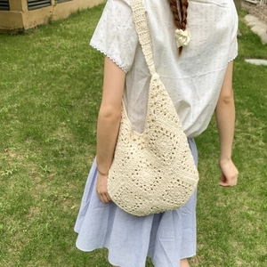 Detail view of beige hand-crocheted tote bag with floral knit patterns on a shoulder strap