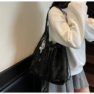 Close-up of black marble texture bucket bag featuring drawstrings and butterfly pendant