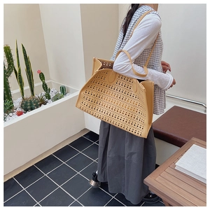 Détails de la découpe au laser sur un sac cabas beige en cuir porté par un mannequin
