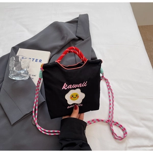 Dettaglio della borsa a secchiello in tela nera con ricamo di uovo fritto e corde colorate