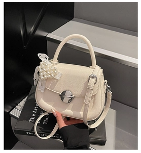 Détail du sac selle beige froissé avec fermoir argenté et charm cœur en perle