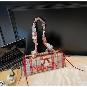 Detail of red, white, and blue plaid shoulder bag with a white heart and ruched handle strap