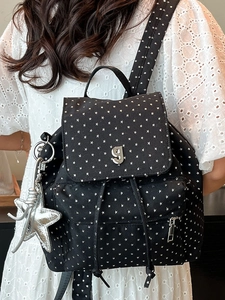 Black backpack with white star patterns and silver G logo shown on a model in white dress