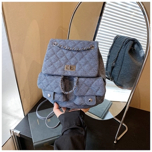 Detailed back view of denim backpack showing quilted pattern and metal chain straps