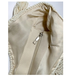 Detail of the beige woven bag showing silk-like inner lining and silver metal zipper closure