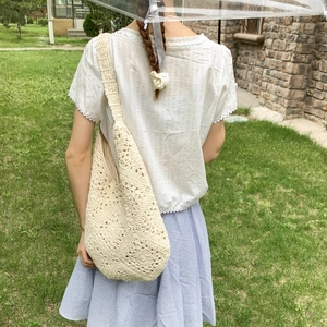 Detail view of woven shoulder bag with hollow geometric patterns and wide strap