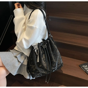 Detail view of black marble texture bucket bag with silver butterfly charm and drawstrings