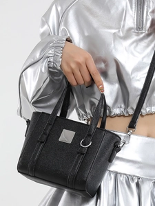 Secchiello nero alla moda con tracolla e placca d'argento su sfondo bianco neutro