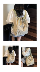 Detail view of beige nylon drawstring backpack with light green straps and front pocket