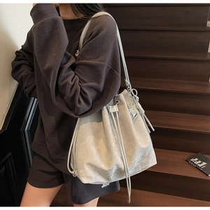 Detail of silver gray bucket bag with drawstring closure and butterfly charm