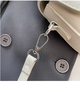 Détail du crochet en métal argenté et de l'anneau en D sur la bandoulière du sac ivoire