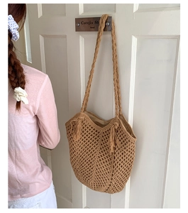 Detail of crochet tote bag with openwork mesh pattern and decorative side tassels