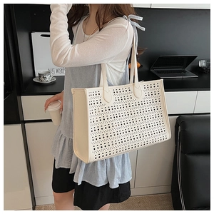 Gros plan détaillé du motif ajouré au laser sur ce sac cabas en cuir de couleur blanc crème