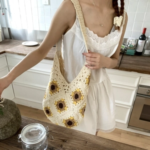 Detail of hand-crocheted sunflower patterns on a beige woven tote bag for summer vacation