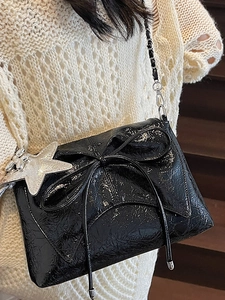 Black ballet-style pleated shoulder bag with metallic bow and silver star pendant charm