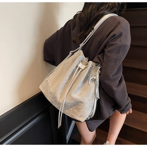 Silver grey drawstring bucket bag with pearlescent finish and butterfly charm on model