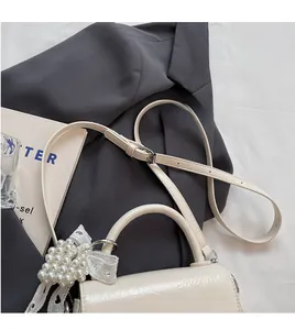 Détail du sac beige avec texture plissée brillante et nœud décoratif en perles