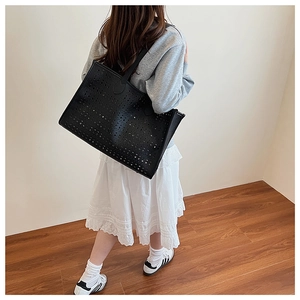 Gros plan sur le sac fourre-tout noir avec motifs ajourés au laser et texture en PU